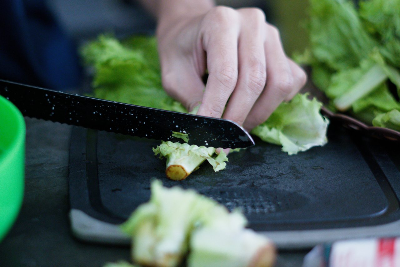 Hand cutting the root from a head of fresh lettuce