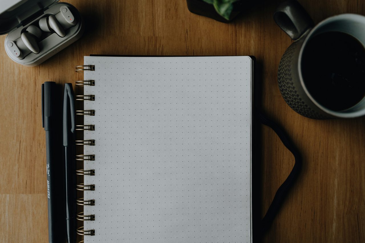 Notebook, pen, headphones and coffee on a desk