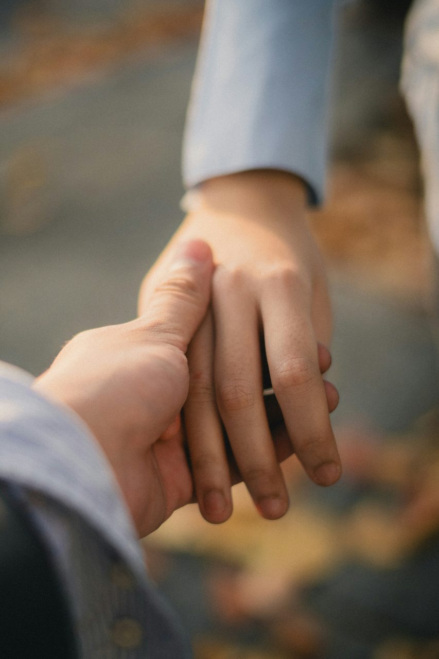 Two people gently holding hands
